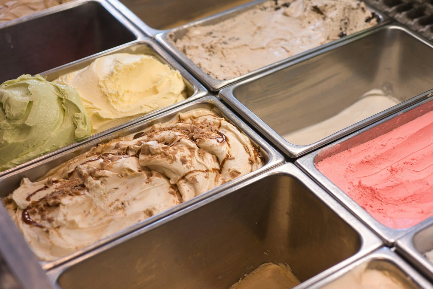 Vari gusti di gelato esposti in lucide vaschette di acciaio inox.