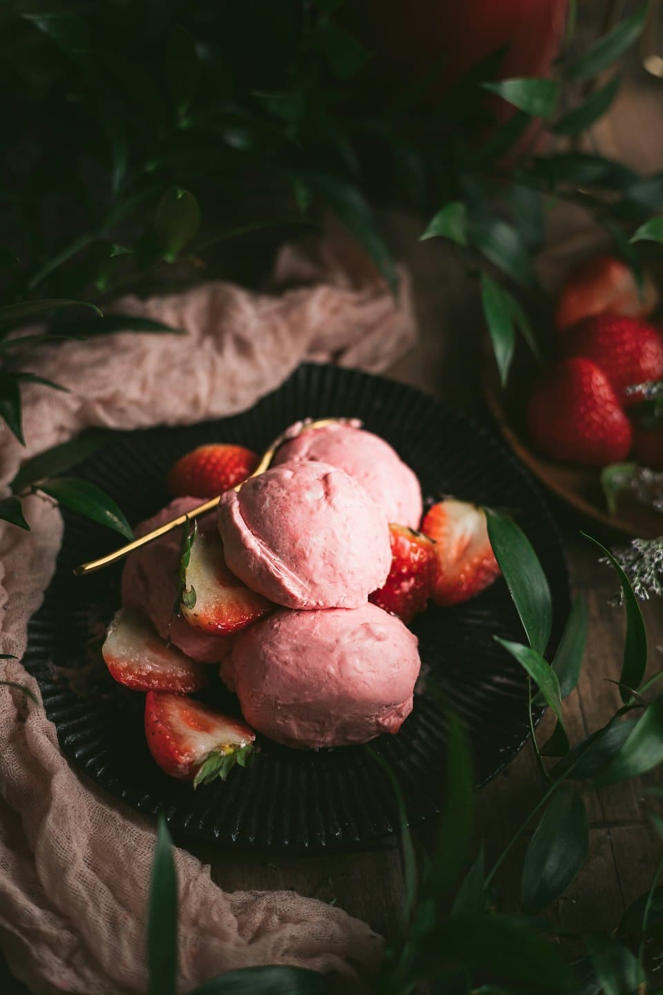 Palline di gelato alla fragola con fragole fresche su un piatto.