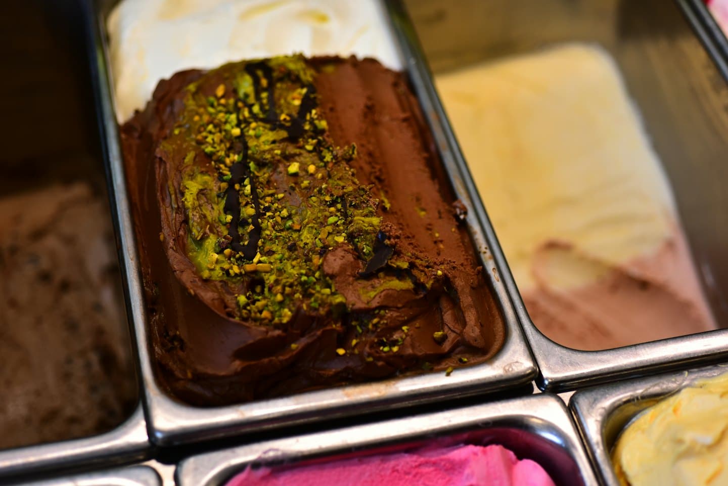Assortimento di gusti di gelato artigianale esposti in vaschette metalliche.